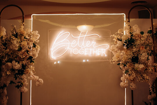 Wedding Photo Backdrop with "Better Together" Neon Sign and Flowers