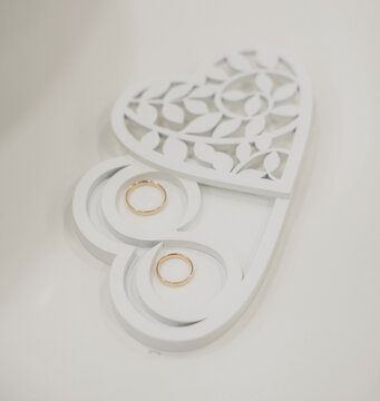 Close-Up of Gold Wedding Rings on Elegant Heart-Shaped Stand