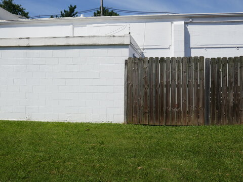 A cinderblock wall painted white and a wooden fence