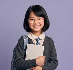 Obraz premium Portrait of a smiling young Asian schoolgirl wearing glasses and holding a notebook against a purple studio background