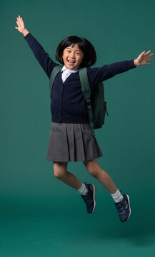 Happy schoolgirl with arms raised jumping in school uniform