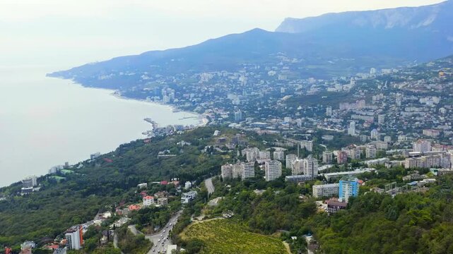 Yalta, Crimea. Panorama of the city in sunny weather. Embankment and port. Drone footage