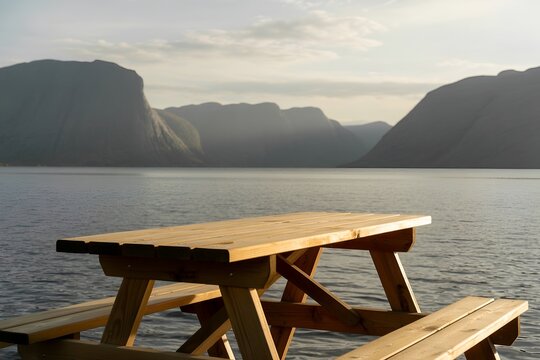 Wooden picnic table overlooking calm blue fjord water and majestic mountains scenic outdoor nature scenic view landscape