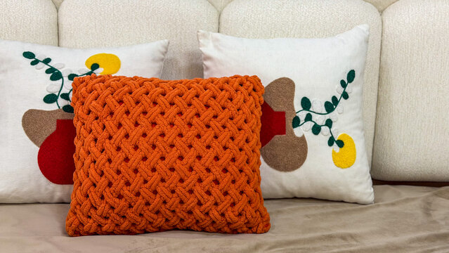 Cozy modern sofa styled with a chunky knitted orange cushion and decorative pillows, warm contemporary home interior with textured textiles.