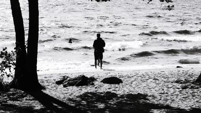 A single individual standing on a beach in black and white