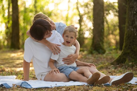 Smiling mother with her sons outdoors, playful family moment, summer fun and Mothers Day concept. 