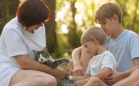 Mother embracing sons in a warm summer forest, showing love, care, and family bond during golden hour