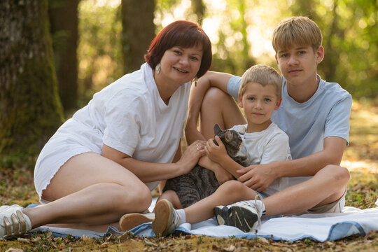 Smiling mother with her sons outdoors, playful family moment, summer fun and Mothers Day concept. 