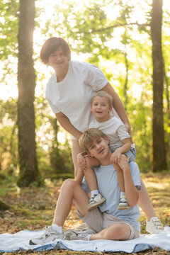 Smiling mother with her sons outdoors, playful family moment, summer fun and Mothers Day concept. 