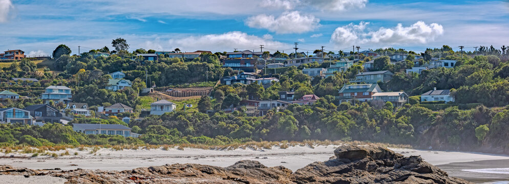 Wohnhaeuser am Huegel ueber dem Sandstrand von Brighton bei Dunedin Neuseeland