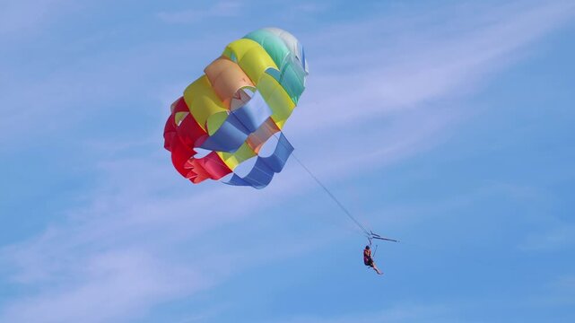 Thrilling experience of parasailing, offering tourists a breathtaking view from the sky, over the sparkling sea in 4k slow motion 60fps