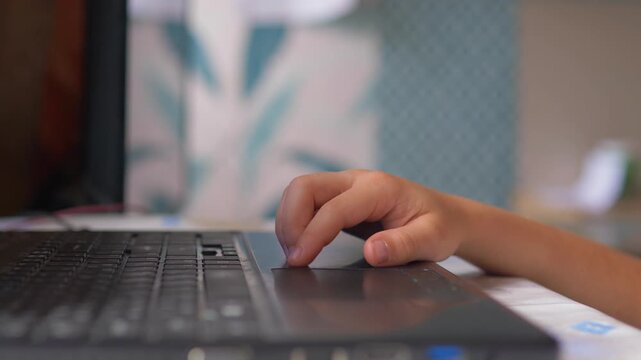 child's hand thoughtfully tapping a finger on a laptop computer while thinking