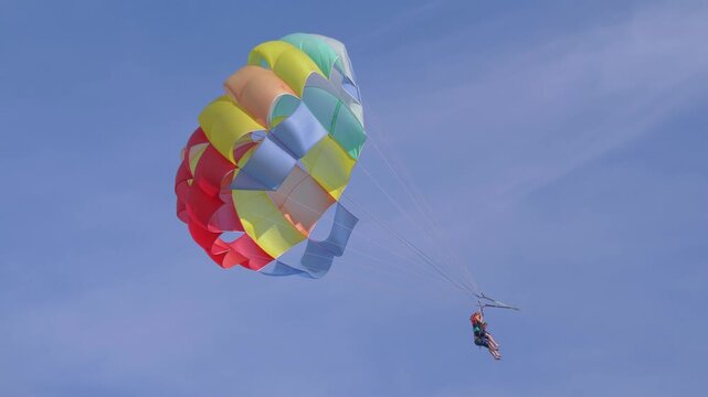 Thrilling experience of parasailing, offering tourists a breathtaking view from the sky, over the sparkling sea in 4k slow motion 60fps