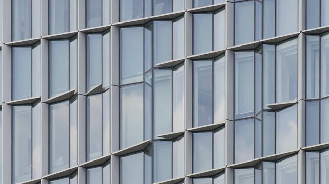 Glass facade of modern building reflecting clouds