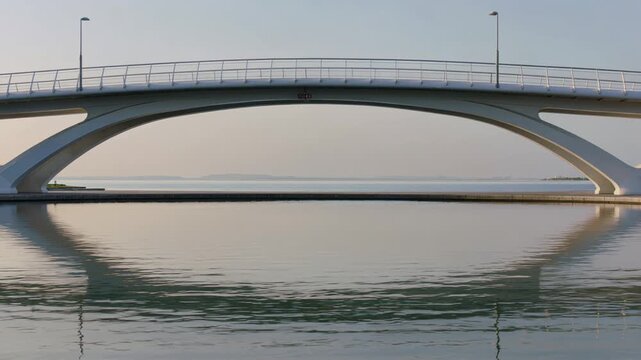 Modern arch bridge reflecting in the calm water