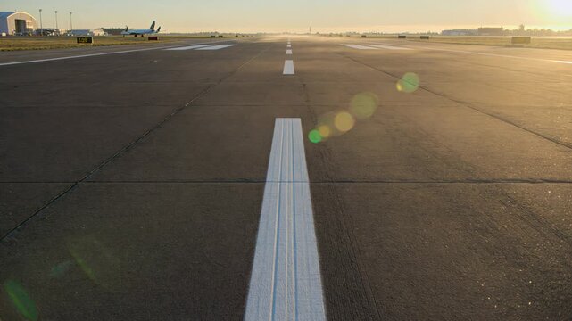 First-person view moving down an empty airport runway at sunrise