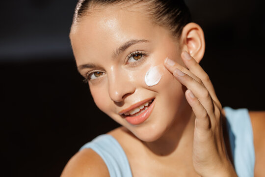 Young Woman Applying Cream for Perfect Skin Care