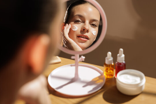 Face cream skincare routine with Korean style cosmetics at mirror