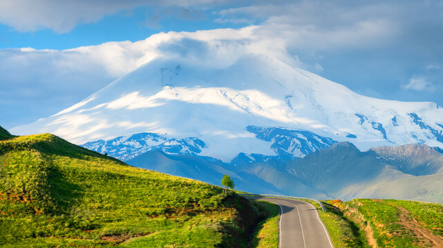 View of Elbrus mount with clouds at sunrise. Road of Gil-Su valley in North Caucasus, Russia.