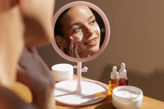 Woman Applying Homemade Facial Cream in Mirror