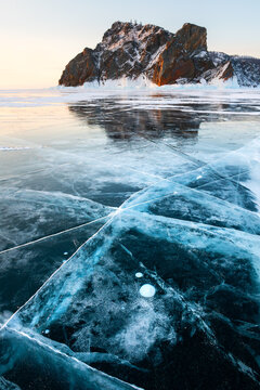 Blue transparent cracked ice on Baikal lake in winter. Khoboy cape of Olkhon island, Baikal, Russia.