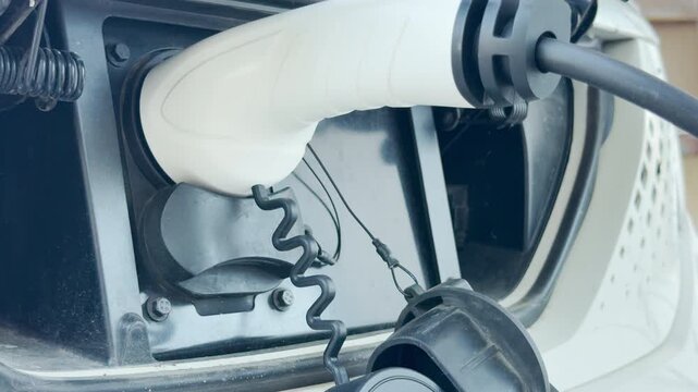 The electric car charging cable plugs into the port, powering the vehicle efficiently. This clean energy process evokes a hopeful and modern feeling for a sustainable future.