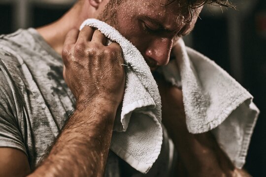 Exhausted Athlete Drying Sweaty Face with Towel