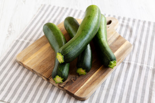 Raw Green Organic Zucchini on a Wooden Board, side view.