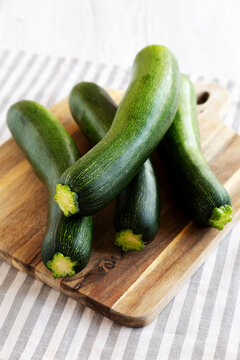 Raw Green Organic Zucchini on a Wooden Board, side view.