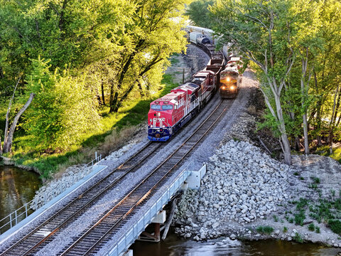 Savanna, Illinois May 10, 2026 CPKC 776 America 250 locomotive passing a second freight train on parallel tracks through a lush green forest