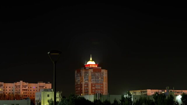 A glowing dome atop a high-rise building at night.
