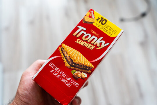 Warsaw, Poland - Aug 11, 2026: Hand holding a Ferrero Tronky Sandwich wafer box with a pack of ten