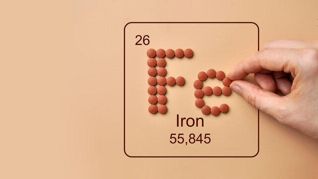 Hand Arranging Iron Fe Element Symbol from Supplements