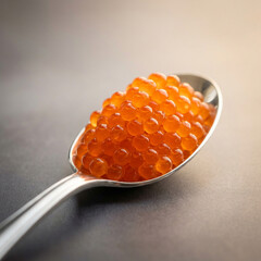 Obraz premium Fresh red salmon caviar on a silver spoon close-up. Luxury seafood appetizer on a dark background.