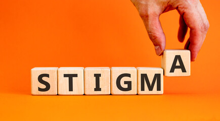 Naklejka premium Stigma word symbol. Concept word Stigma on beautiful wooden blocks. Beautiful orange background. Psychologist's hand. Business psychological stigma word concept. Copy space.