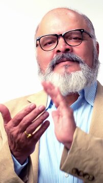 Indian Asian elderly businessman with beard, standing in a suit against a white background, clapping hands with a happy and joyful expression