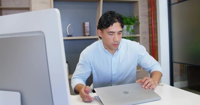 Man in shirt checking laptop at office, closing, tucking phone and carrying laptop to leave
