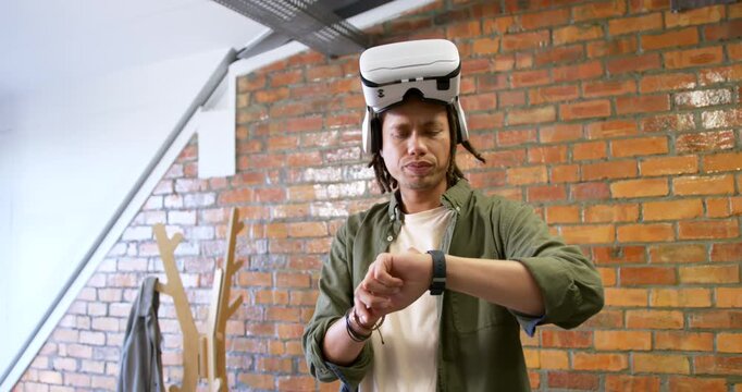 African American man wearing green tee in studio tapping smartwatch after notification, VR on head