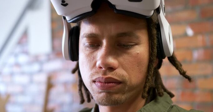 Adult man white headset over-ear cups blinking, looking down in studio, left light causing flutter