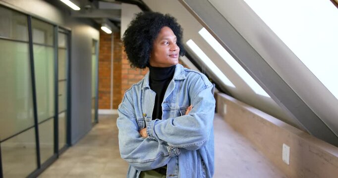 African American man in corridor shifting gaze, skylight drawing gaze, leaning on ledge and smiling
