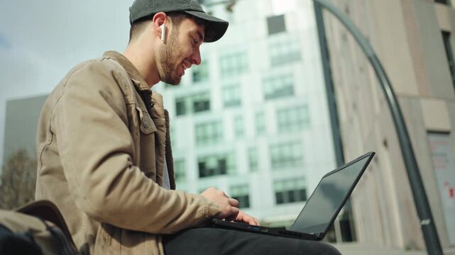 Young male freelancer working on online video call meeting on laptop in the city