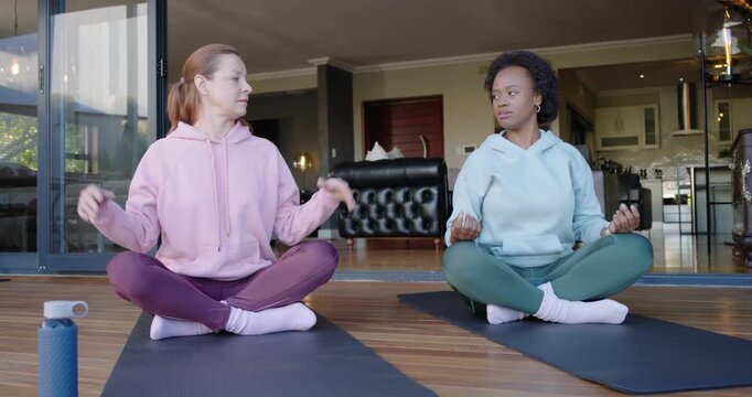 Diverse women checking smartwatch glancing guiding breathing meditating on black mats on deck