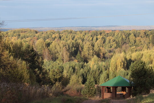 a gazebo on the edge of an autumn forest on a sunny day