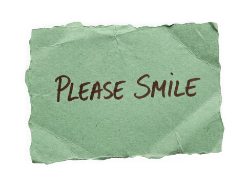 Green ripped paper note with the handwritten text please smile written on it