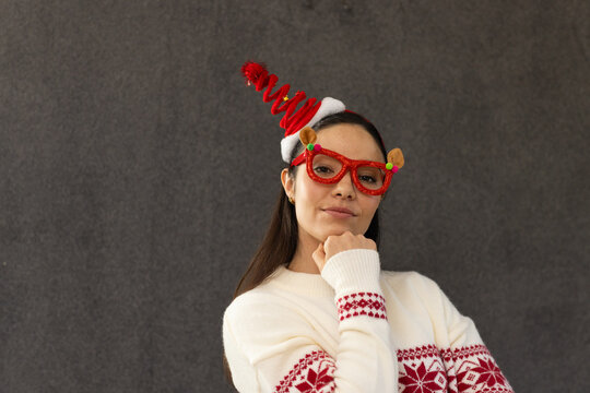 Female posing in studio, hand under chin, wearing Nordic sweater, reindeer glasses, spiral headband
