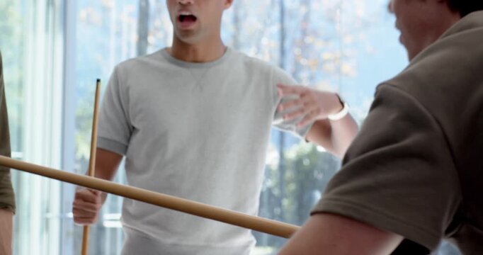 African American man with cue laughing, celebrating after pal shooting on pool table by glass
