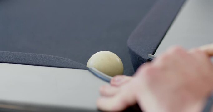 Man steadying hand on pool rail as ball shifting at pocket-seam, cue aligning, aiming pocket shot