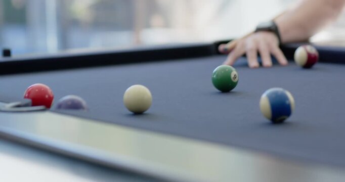 Player drawing back cue, striking cue ball, sending balls toward left pocket on table to score