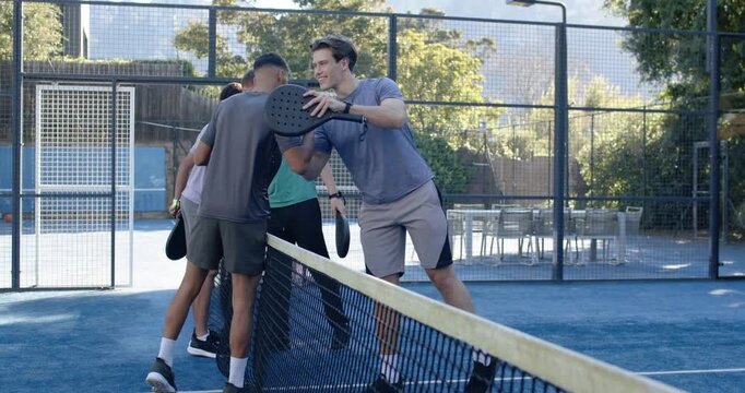 4 men moving to net after match ending, giving padel taps, shakes, hugs, showing respect courtside