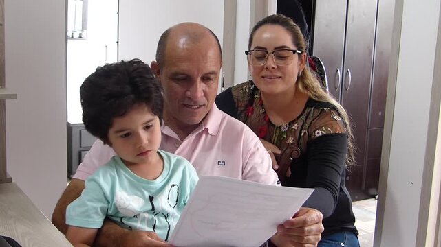Happy family with parents and young son smiling while reviewing and reading important paper documents or contracts together at home